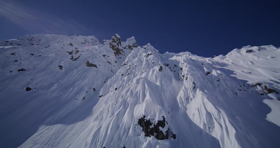 Rough terrain of snow covered mountains under a clear blue sky