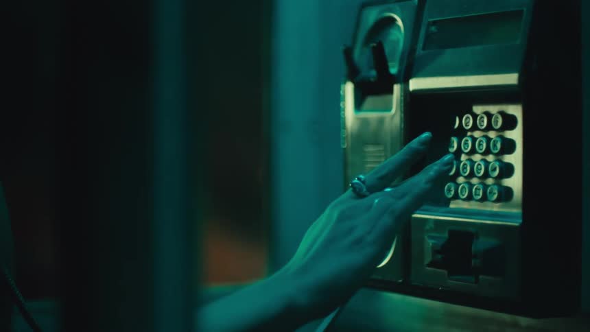 The woman dials the phone in the booth