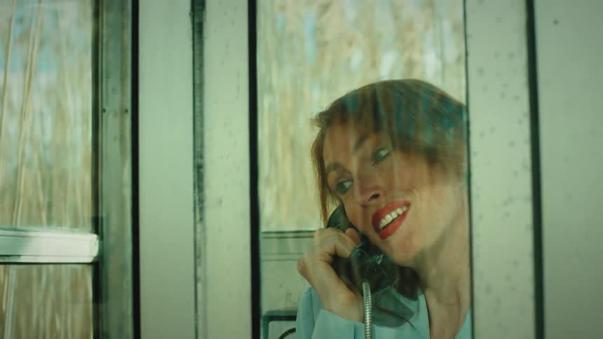 The woman is in the phone booth talking