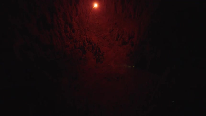 Bright controlled device trails smoke while flying up and down above the forest at night