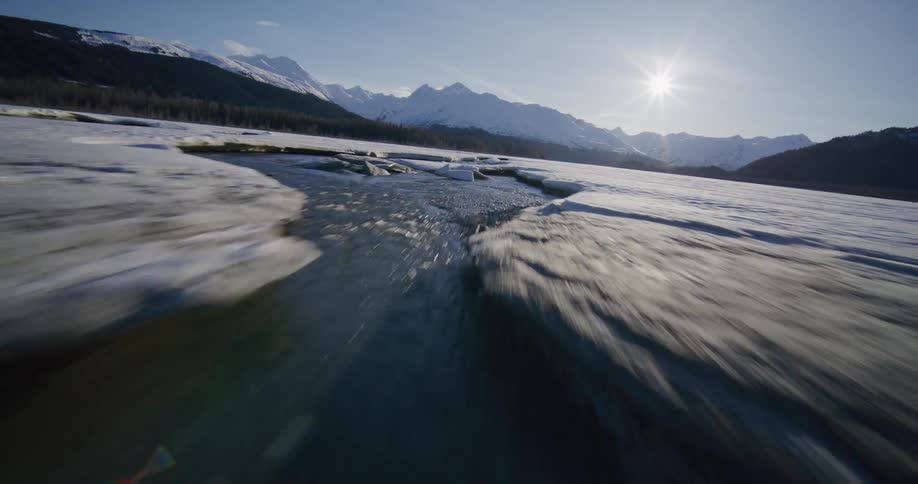 Streams on a valley covered in snow and ice with mountains on the background outdoors during day time