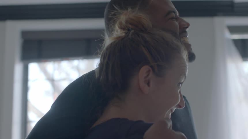 A man and woman hug while talking and laughing