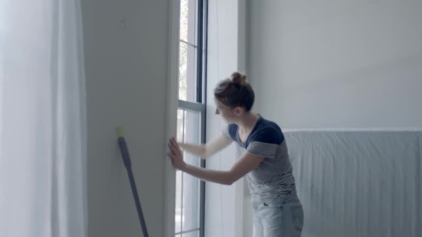 A woman sprays cleaner and then wipes down the window