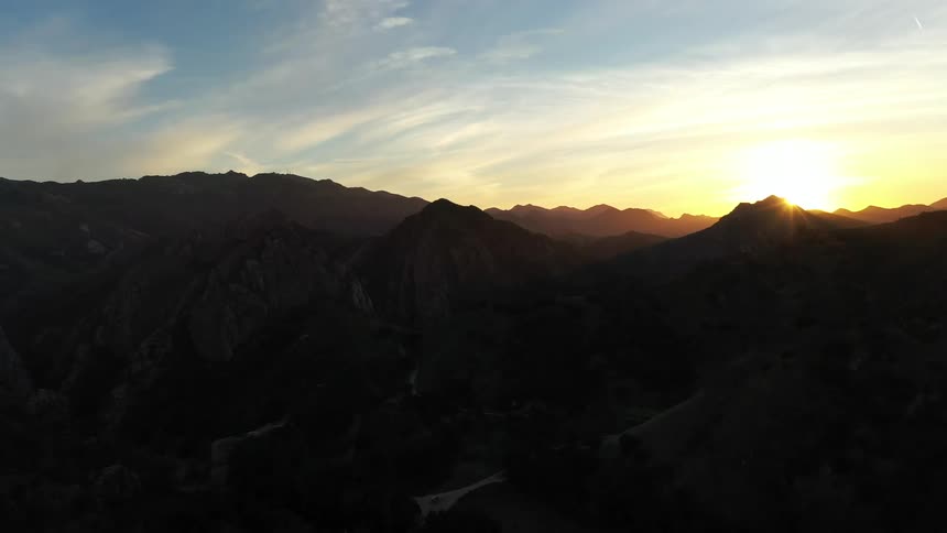 A view of a mountain range with the sunlight in the distance