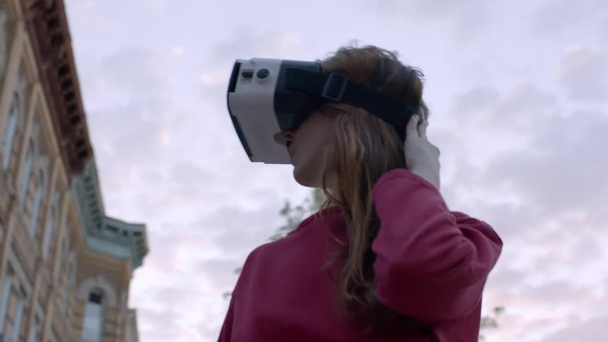 Woman wearing virtual reality headset outside is looking around