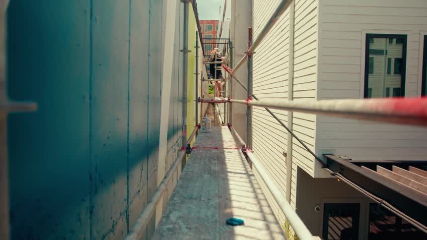The man climbs up the scaffolding by the home
