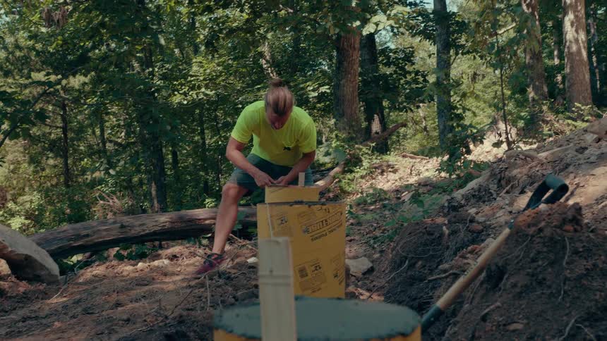 The man is tying rope to the wooden stake