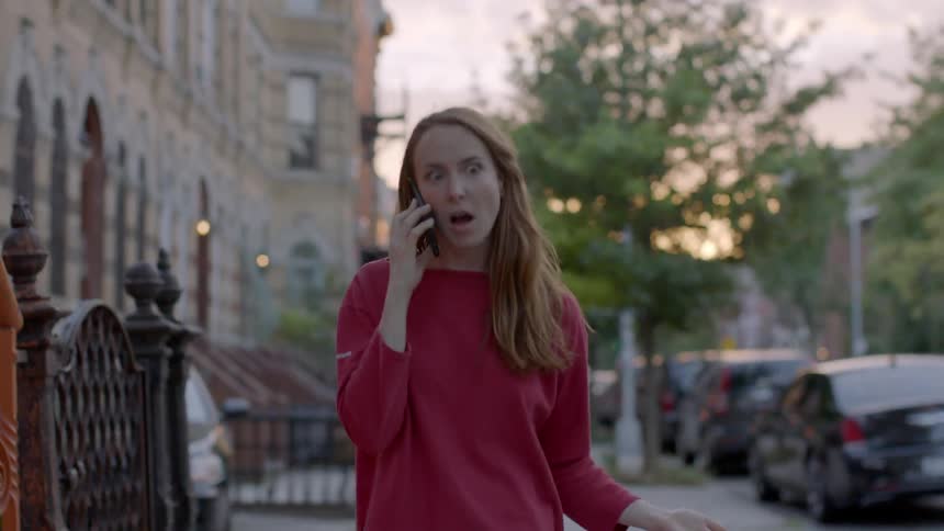 A woman in a red shirt argues on the phone outside