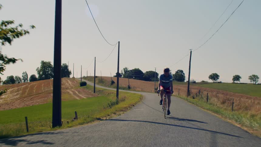 Man rides his bicycle on a rural road across the countryside