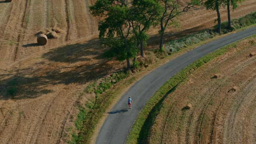Man rides his bicycle around the curve on a rural road