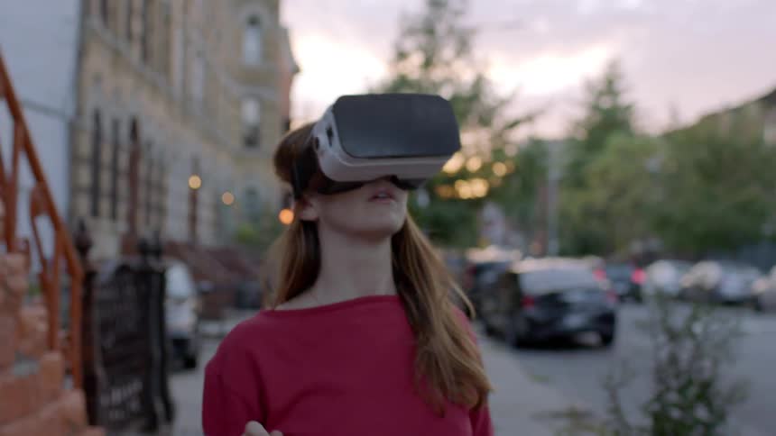 A woman is looking around at her neighborhood as she wears a vr appliance