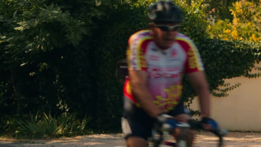 The men ride by in a line on bicycles
