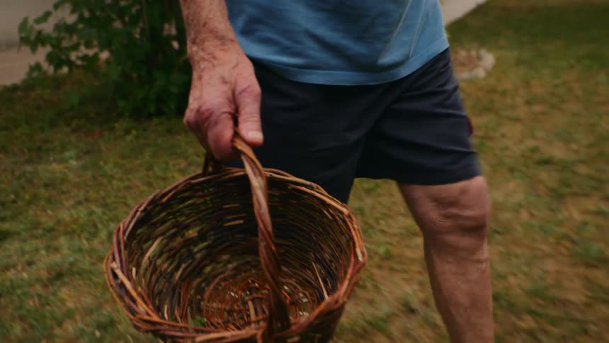 The man carries a basket in the yard