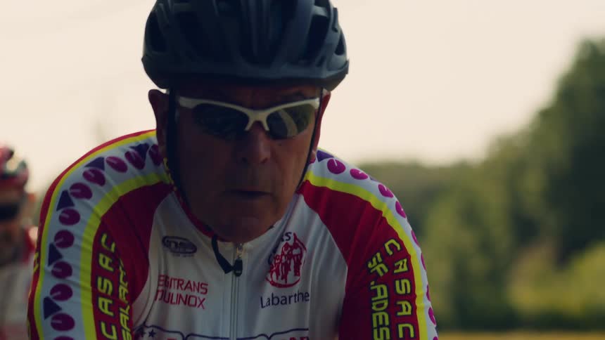 The men are cycling together while wearing helmets