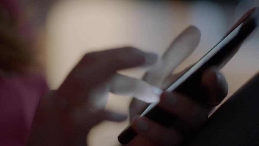 A woman types on her phone