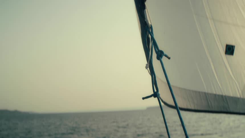 Sail on a boat over sea waters close to the land outdoors during dusk or dawn
