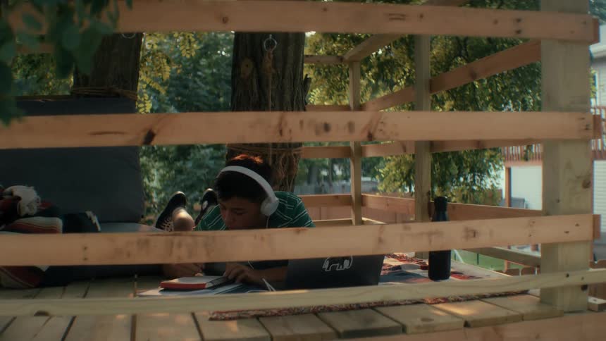 Boy studying for a test in a wooden treehouse