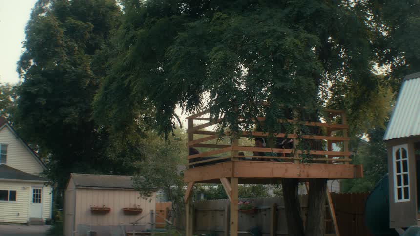 Youth lying in a treehouse listens to music on an autumn day