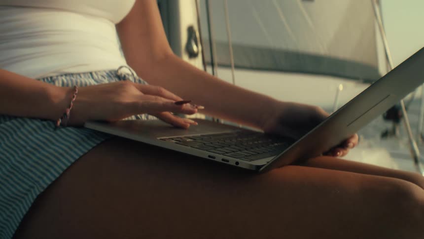 Young woman sitting on a boat with her laptop computer