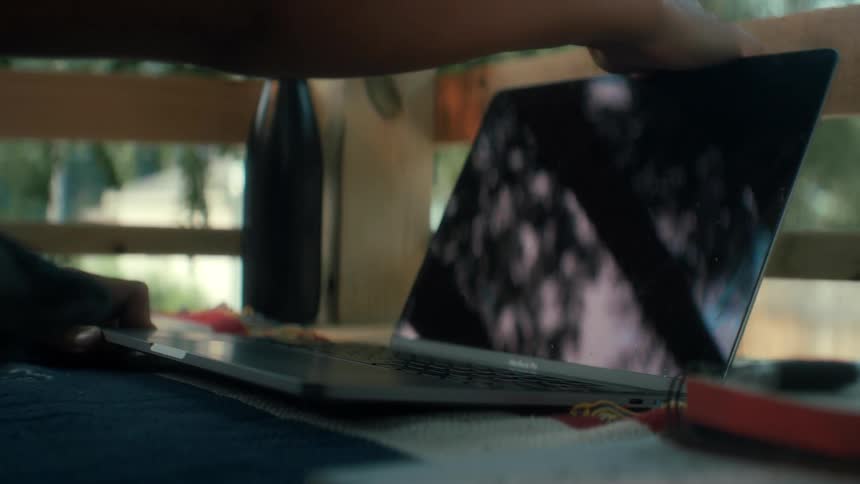 A person opens his laptop to do schoolwork outside