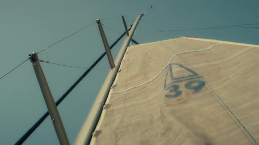 Boat sail with number 39 viewed from below against a blue sky