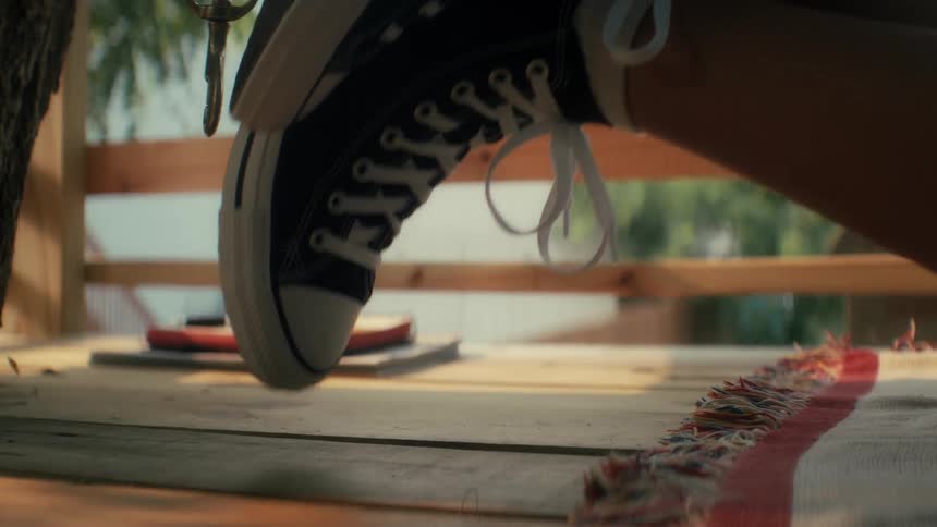 A person wearing a black sneaker with white laces is tapping their feet and toe tapping carefree