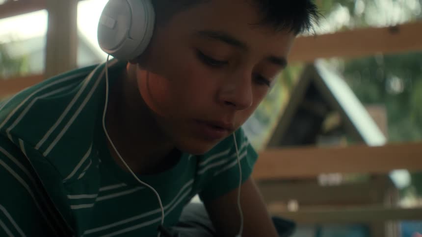 The boy excited to learning and energetically note taking in his notebook in the backyard