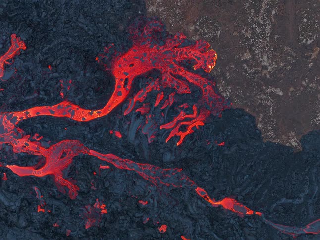 Glowing molten hot lava flows from an erupting volcano