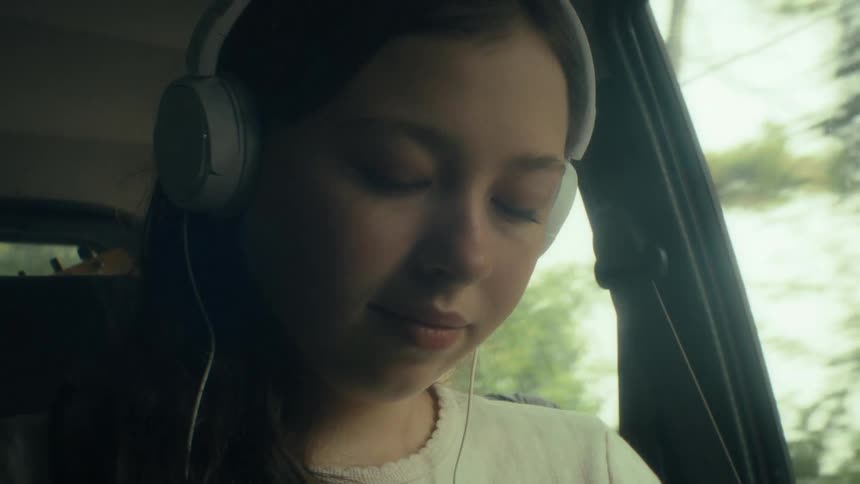 Girl wearing headphones inside a car