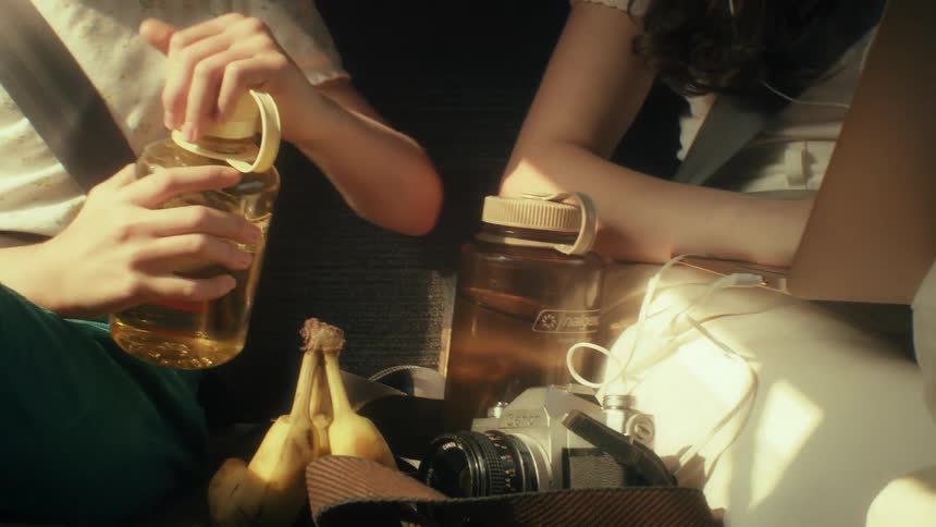 Person holds yellow bottle beside bananas and connected cables