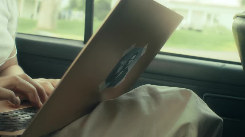 Person typing on a laptop inside a car