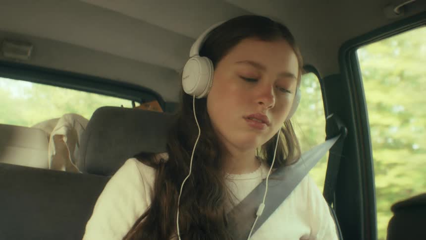 The girl listens to headphones while riding in the car
