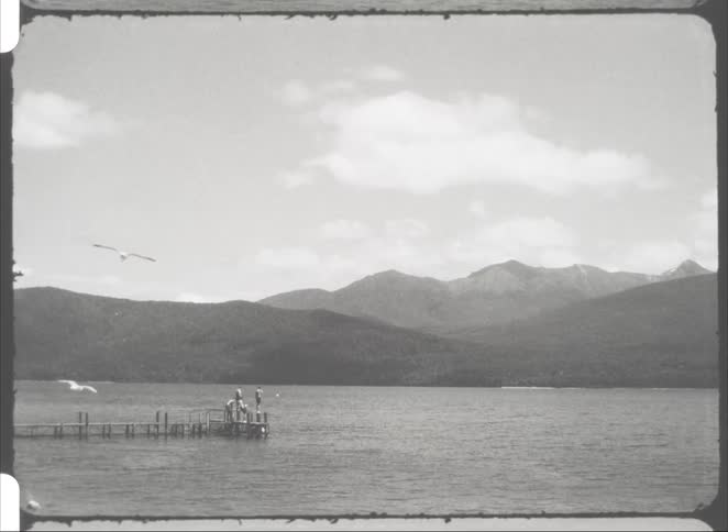 People on a wooden pier in the sea with a mountain in the background