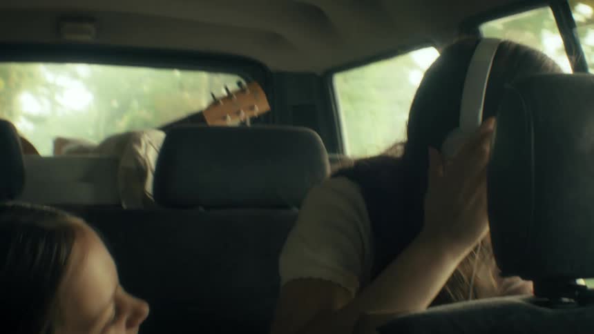 A young girl in the backseat excitedly points out the window causing her older sister to look