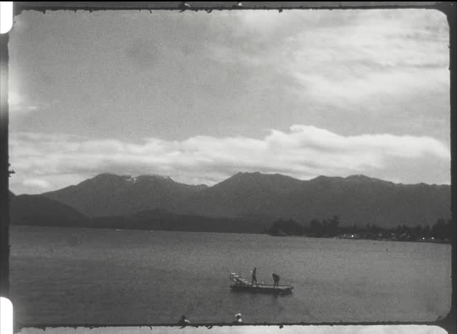 Two people in a canoe on the lake with mountains in the background