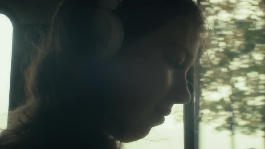The girl listens to headphones while riding in the car