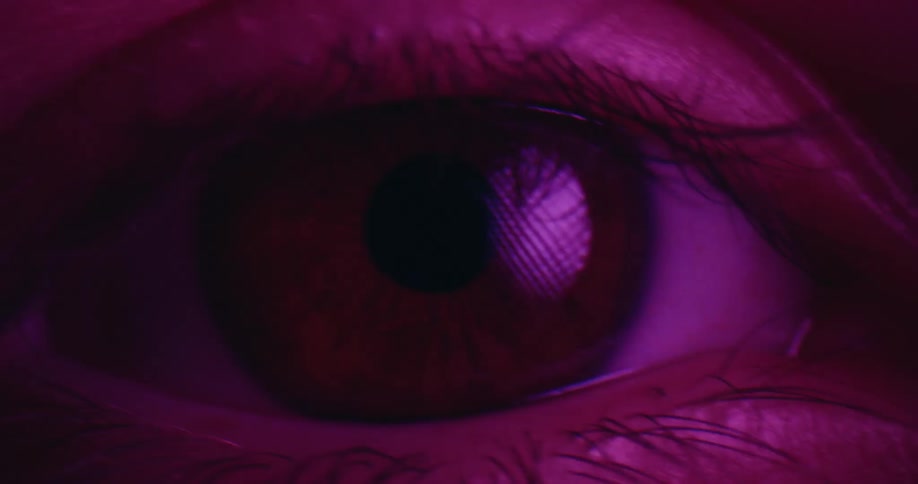 A womans eye with brown irises and black eyelashes catches the light a soft reflection shimmering across the surface
