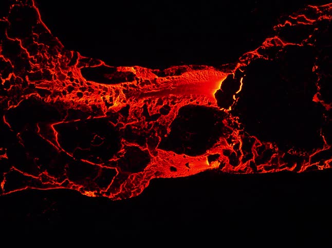 Glowing molten hot lava flows from an erupting volcano
