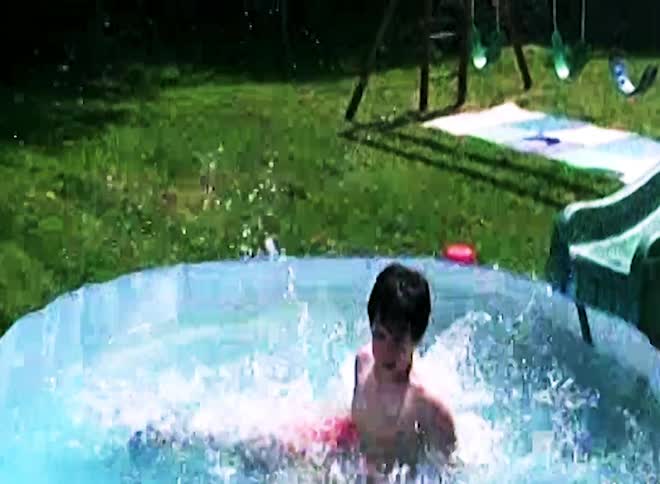 Boy slides down a slide and falls into an inflatable pool