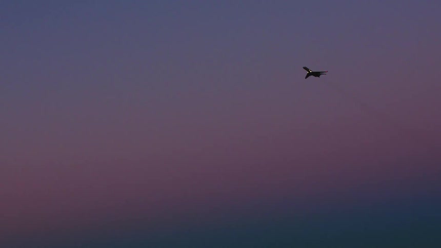 Airplane flying over an urban area at dusk with illuminated buildings in the background