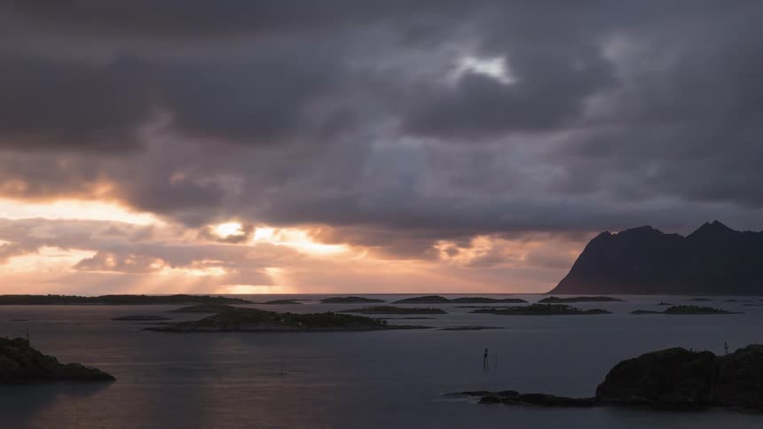 The clouds move past the setting sun over the water