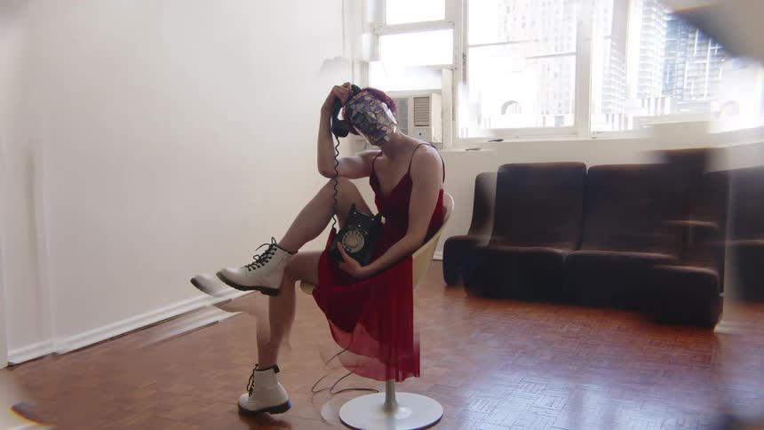 The woman wearing a red dress and metallic mask is holding a phone