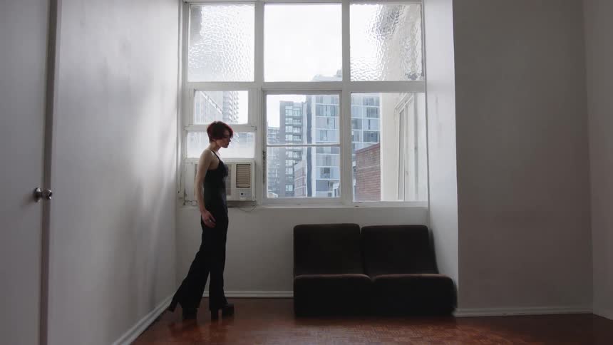 The woman stands by her couch