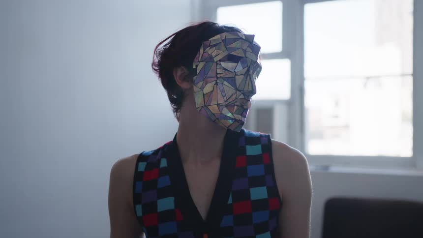 The light reflects on the womans metallic mask