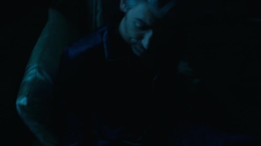 Adult couple sitting in bed reading books before they react to flashing lights on the outside and the man rushes to pick up a tool from a drawer next to the bed indoors during night time