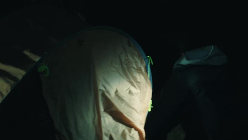 Tent being set up in a dark environment with the help of a headlamp