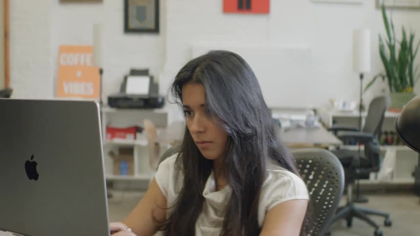 Woman stops to sit staring at her computer after typing on it in an office during the daytime