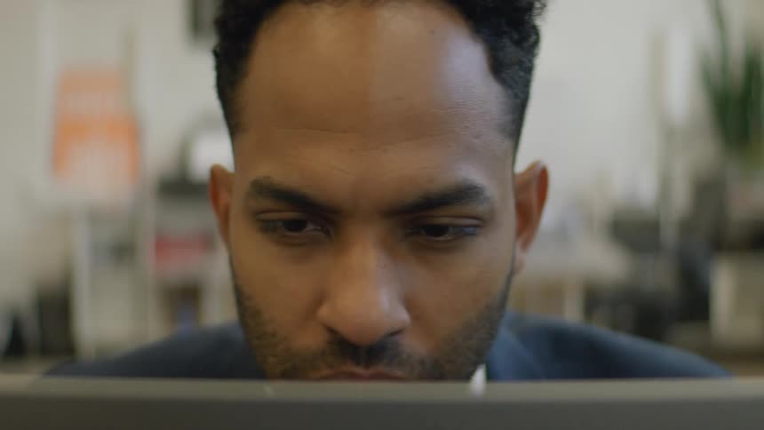 Man focused on a laptop screen in an indoor office setting