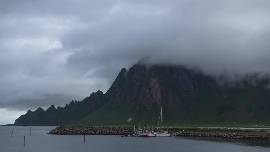 Clouds pass by above a lake and a mountain