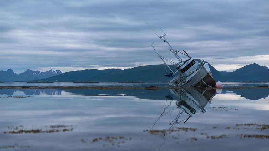 A shipwreck in a fjord on a cloudy day